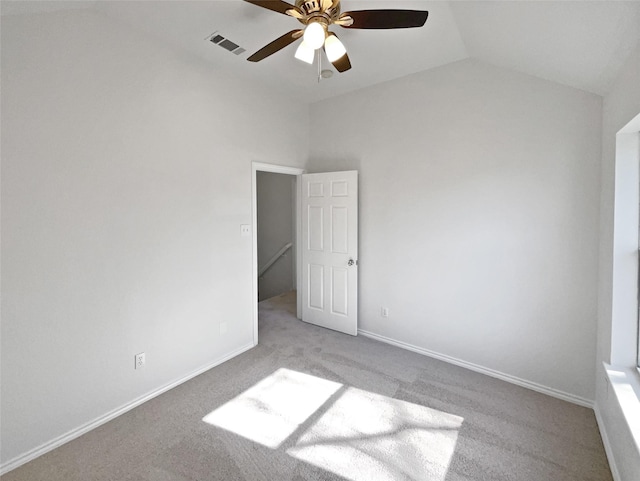 unfurnished bedroom with lofted ceiling, light colored carpet, visible vents, ceiling fan, and baseboards