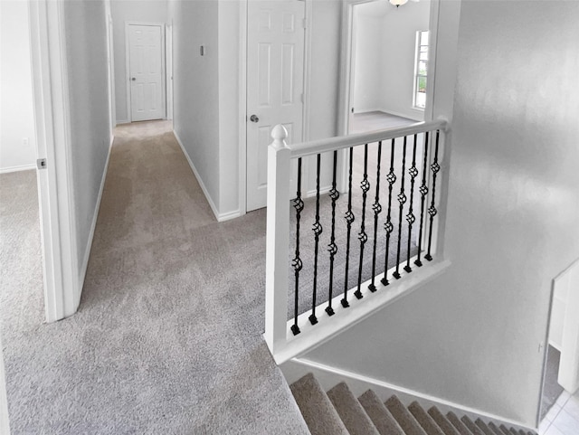 hallway featuring light carpet, baseboards, and an upstairs landing