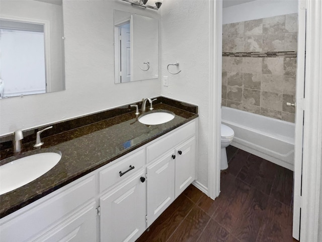 full bathroom featuring toilet, double vanity, a sink, and wood finished floors