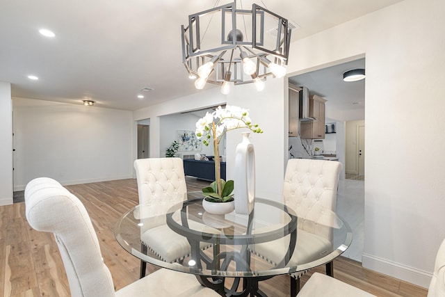 dining area featuring light wood-style flooring, baseboards, and an inviting chandelier