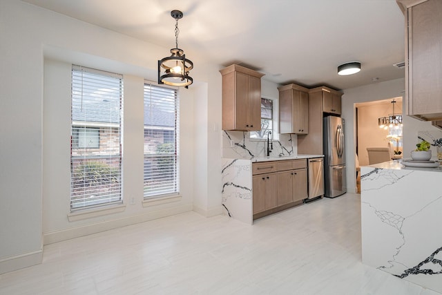 kitchen featuring baseboards, decorative backsplash, appliances with stainless steel finishes, decorative light fixtures, and a sink