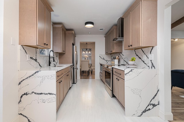 kitchen with light stone counters, stainless steel appliances, a sink, decorative backsplash, and wall chimney exhaust hood