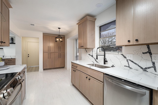 kitchen featuring light brown cabinets, stainless steel appliances, a sink, hanging light fixtures, and backsplash