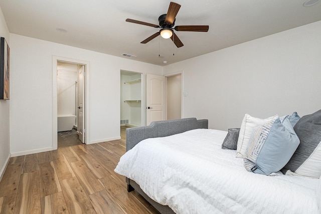 bedroom with a ceiling fan, visible vents, baseboards, light wood-type flooring, and ensuite bath