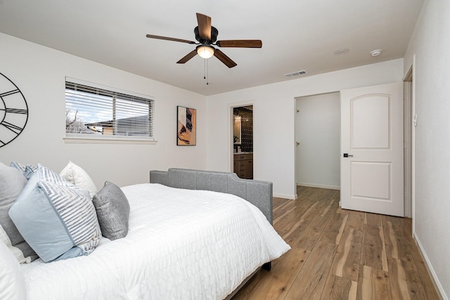 bedroom with a ceiling fan, visible vents, baseboards, and wood finished floors