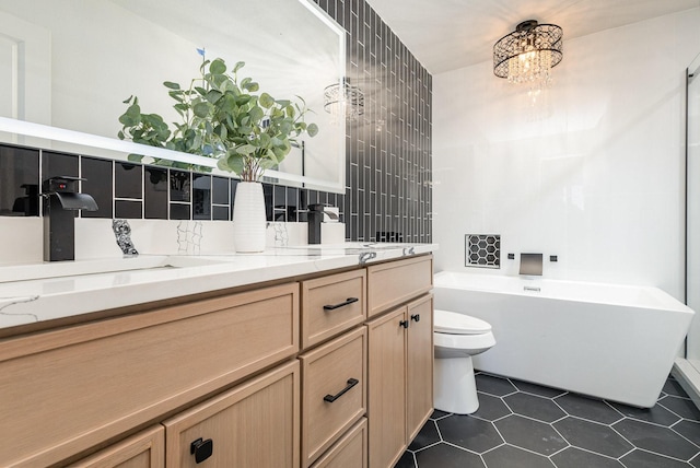 full bath featuring double vanity, a freestanding bath, toilet, a sink, and tile patterned floors