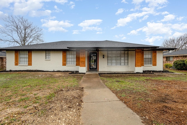 view of front facade featuring a front yard, brick siding, and roof with shingles