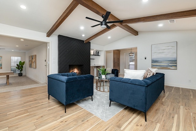 living room featuring vaulted ceiling with beams, a fireplace, visible vents, light wood-style floors, and ceiling fan