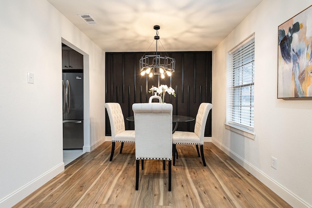 dining room featuring baseboards, visible vents, a notable chandelier, and light wood finished floors