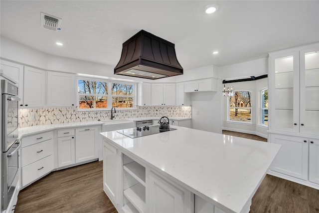 7004 Ledbetter Rd, Arlington, TX 76001 - kitchen with black electric stovetop, premium range hood, a sink, dark wood-style flooring, and a chandelier