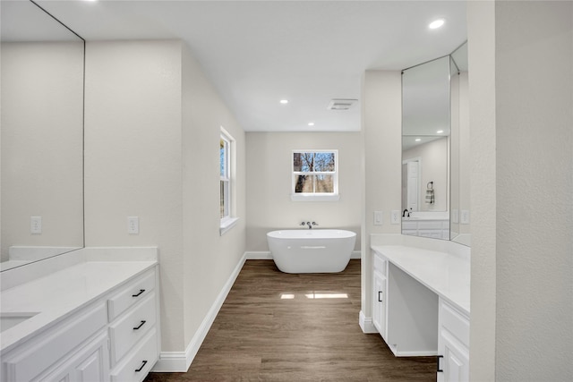 7004 Ledbetter Rd, Arlington, TX 76001 - bathroom with wood finished floors, vanity, a freestanding bath, baseboards, and recessed lighting
