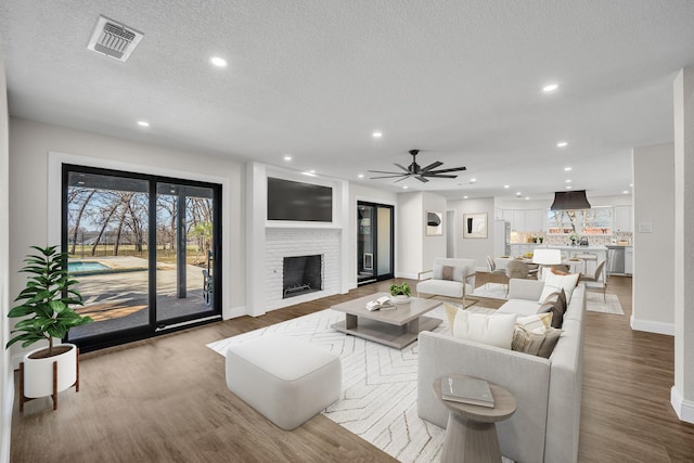 7004 Ledbetter Rd, Arlington, TX 76001 - living room with wood finished floors, baseboards, recessed lighting, a brick fireplace, and a ceiling fan