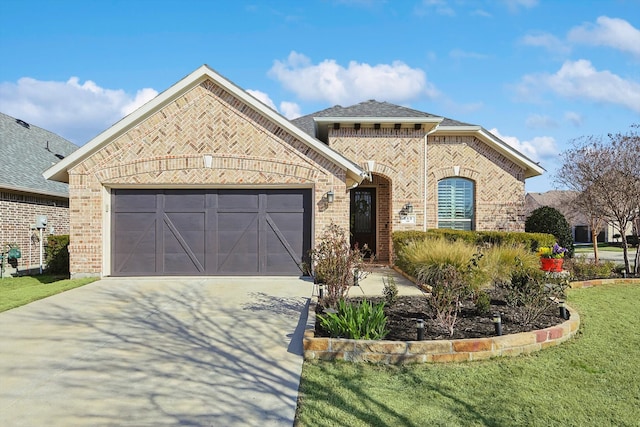 french country home with a garage, brick siding, a shingled roof, concrete driveway, and a front yard