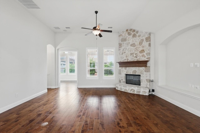 869 Field Xing, Little Elm, TX 76227 - unfurnished living room with ceiling fan, a stone fireplace, hardwood / wood-style flooring, lofted ceiling, and arched walkways
