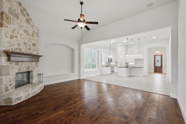 869 Field Xing, Little Elm, TX 76227 - unfurnished living room featuring a ceiling fan, wood-type flooring, a stone fireplace, baseboards, and a sink