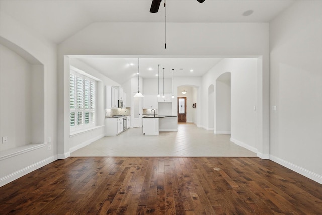 869 Field Xing, Little Elm, TX 76227 - unfurnished living room with arched walkways, ceiling fan, lofted ceiling, light wood-type flooring, and baseboards