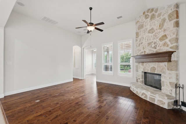 869 Field Xing, Little Elm, TX 76227 - unfurnished living room featuring a stone fireplace, ceiling fan, hardwood / wood-style floors, arched walkways, and baseboards