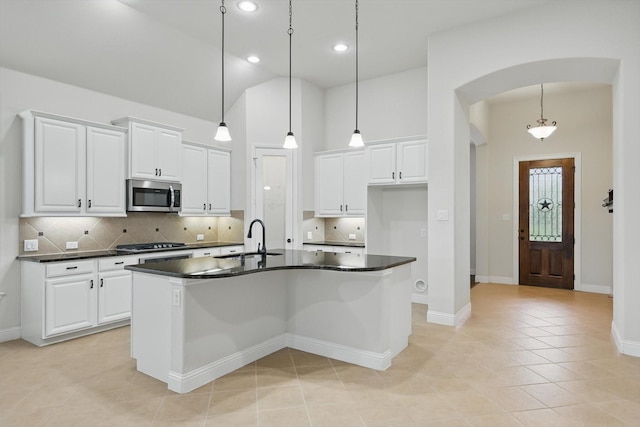 869 Field Xing, Little Elm, TX 76227 - kitchen with stainless steel microwave, a sink, dark countertops, arched walkways, and backsplash