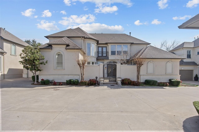 view of front of house with concrete driveway, a fenced front yard, a gate, and stucco siding