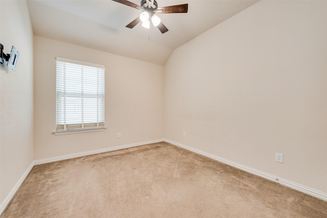 spare room with light carpet, baseboards, vaulted ceiling, and a ceiling fan