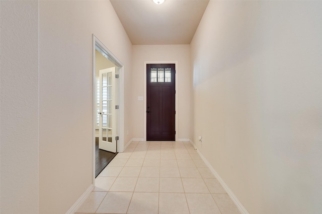 doorway with light tile patterned flooring and baseboards