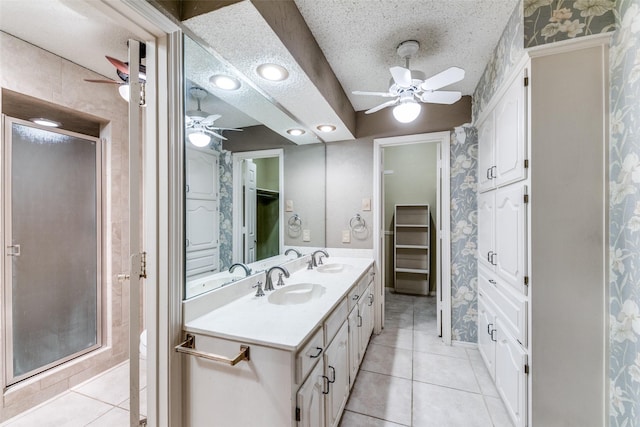 bathroom featuring a stall shower, tile patterned flooring, a walk in closet, and a sink