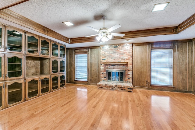 unfurnished living room featuring wooden walls, a fireplace, a textured ceiling, and wood finished floors