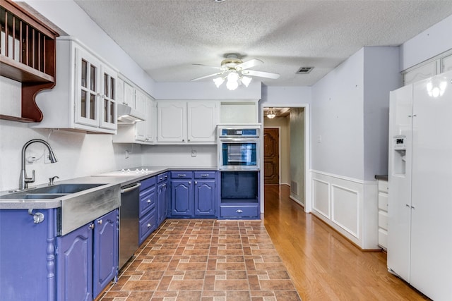 kitchen with blue cabinets, white cabinets, appliances with stainless steel finishes, and open shelves