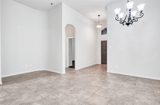 empty room with an inviting chandelier, baseboards, a high ceiling, and arched walkways