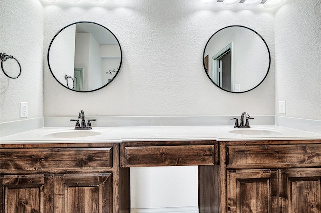 bathroom with a textured wall, double vanity, and a sink