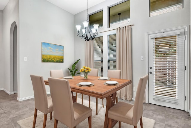 tiled dining space featuring a healthy amount of sunlight, arched walkways, and a chandelier