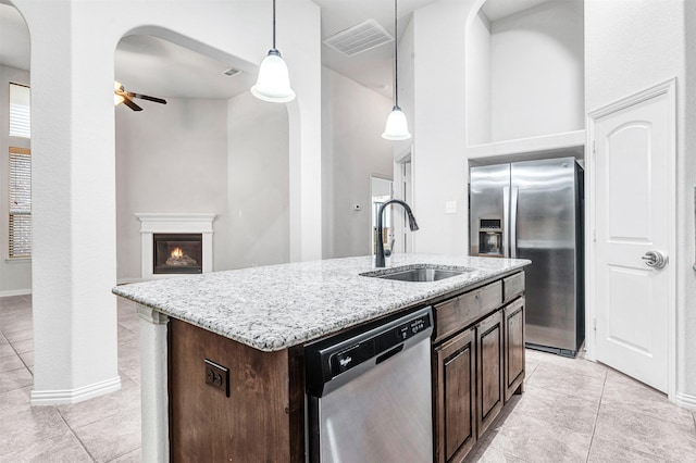 kitchen featuring a kitchen island with sink, a sink, visible vents, appliances with stainless steel finishes, and pendant lighting