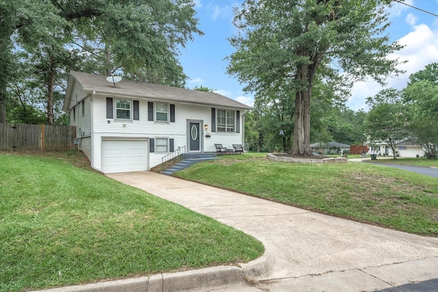 split foyer home featuring a garage, concrete driveway, a front lawn, and fence