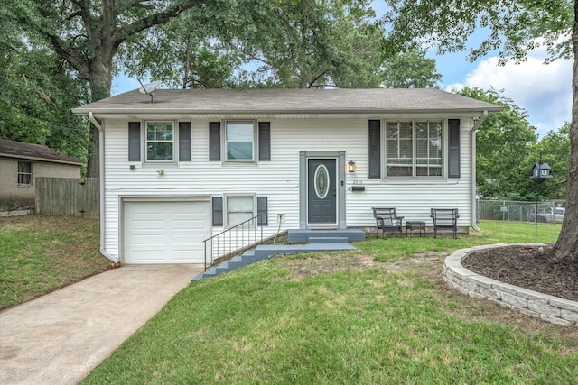 bi-level home with an attached garage, fence, a front lawn, and concrete driveway