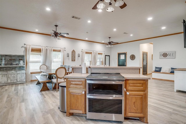 kitchen with range with two ovens, visible vents, a ceiling fan, open floor plan, and light countertops