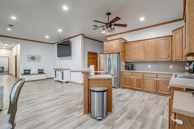 kitchen featuring light wood-style flooring, a center island, freestanding refrigerator, light countertops, and a sink