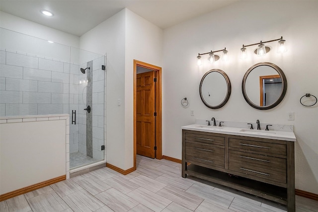 full bathroom with a stall shower, a sink, baseboards, and double vanity