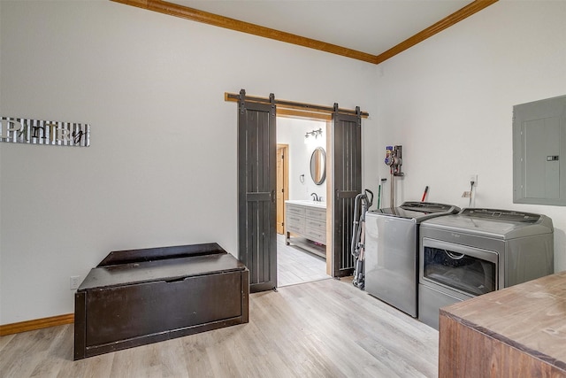 clothes washing area with a barn door, ornamental molding, washing machine and dryer, laundry area, and electric panel