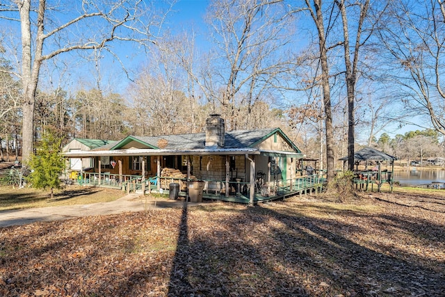 back of house featuring a gazebo, a chimney, and a water view