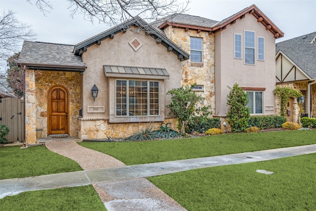 view of front of house featuring stone siding, a shingled roof, stucco siding, and a front yard