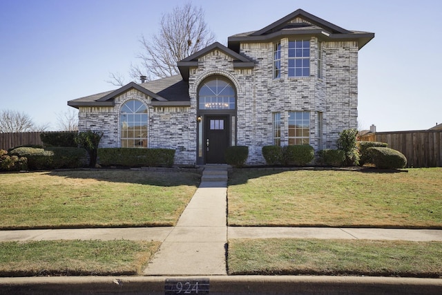 view of front of house with a front lawn, fence, and brick siding