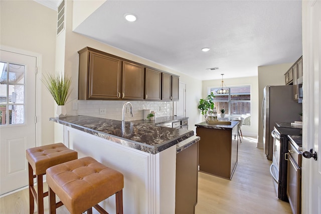 kitchen featuring tasteful backsplash, visible vents, hanging light fixtures, electric range oven, and a kitchen island