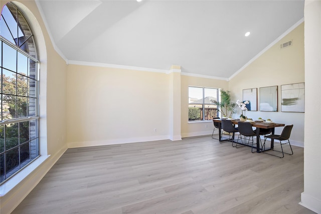 interior space featuring high vaulted ceiling, light wood-style flooring, visible vents, baseboards, and crown molding