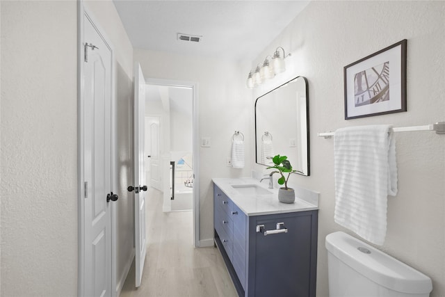 bathroom featuring toilet, visible vents, wood finished floors, and vanity