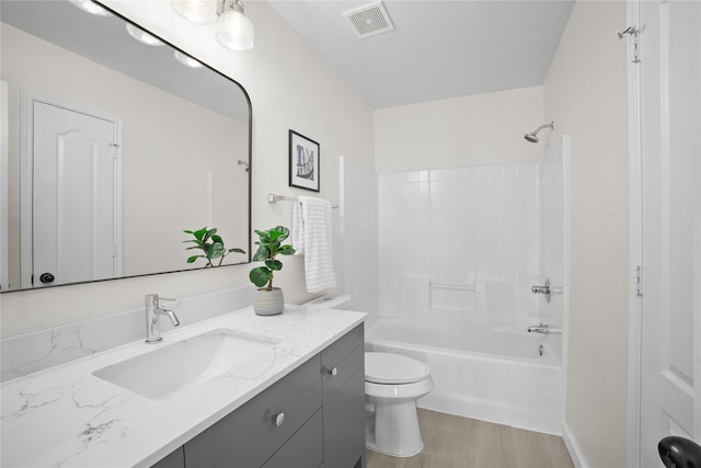 full bath with visible vents, shower / bathing tub combination, toilet, vanity, and wood finished floors