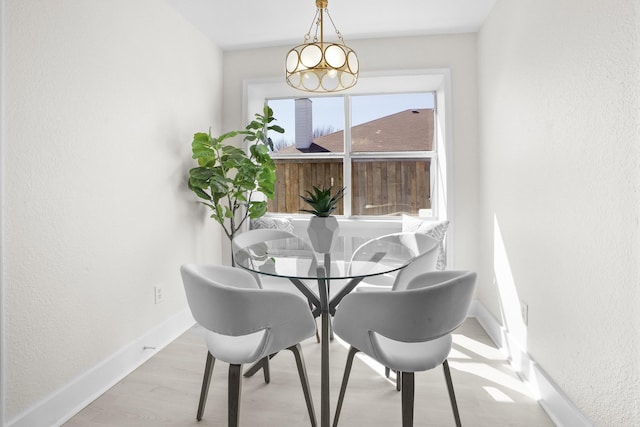 dining space with light wood-style flooring and baseboards