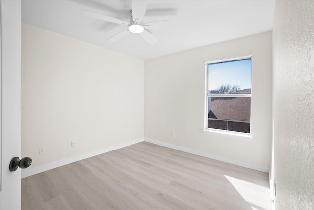 spare room with light wood-type flooring, baseboards, and a ceiling fan