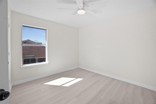 spare room featuring a ceiling fan, baseboards, and light wood finished floors