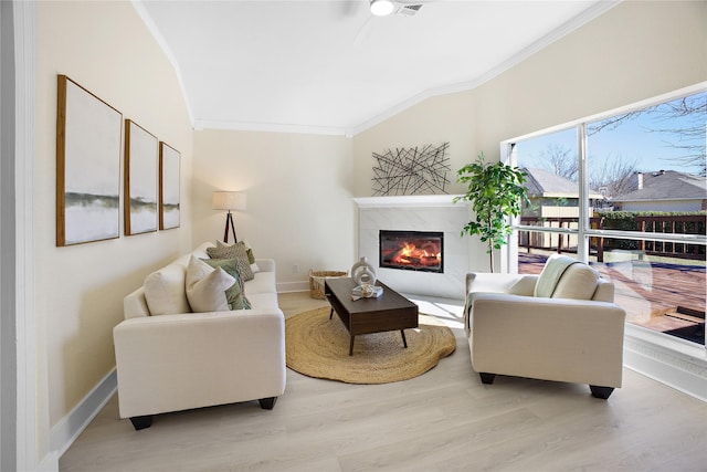 living area featuring ornamental molding, a high end fireplace, baseboards, and wood finished floors