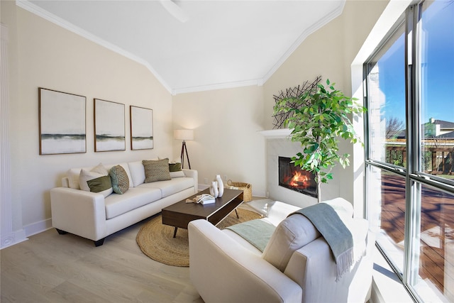 living room with ornamental molding, vaulted ceiling, light wood-type flooring, baseboards, and a tile fireplace